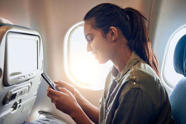 istock beautiful young woman using her smartphone in the plane 938539484