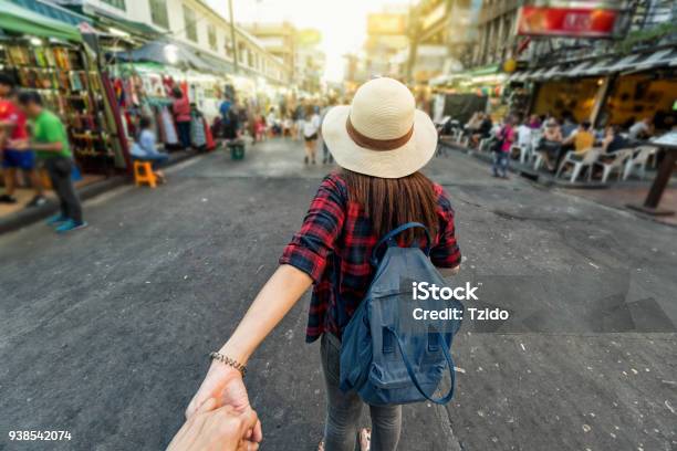 Photo libre de droit de Face Arrière De Jeunes Asiatiques Femmes Voyages Menant En Tenant Son Petit Ami Remettent Khaosan Road Rue Piétonne En Soirée À Bangkok Traveleling Ensemble Et Touristique Avec Suivezmoi Concept banque d'images et plus d'images libres de droit de Sac à dos