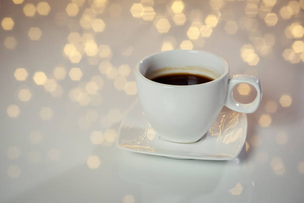 Hot tasty coffee cup on the table with background of blurred holiday lights
