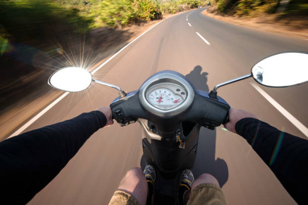 istock Rider driving scooter on an asphalt road. Motion blurred backgro 938558992