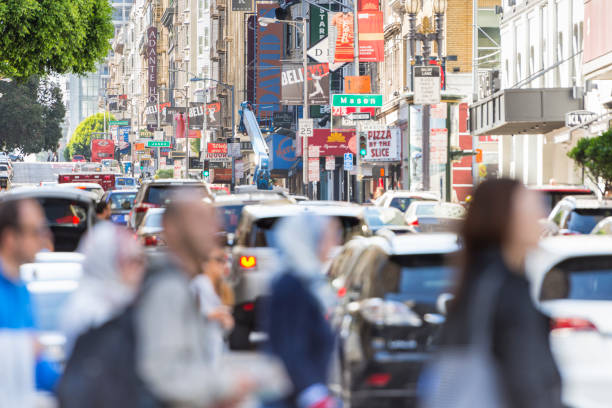 Horizontal color image of the famous Geary Street in downtown San Francisco with unrecognisable people crossing the road with traffic in the background.