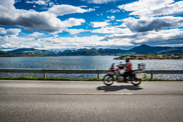 istock Biker rides a road with Atlantic Ocean Road in Norway. 938561180