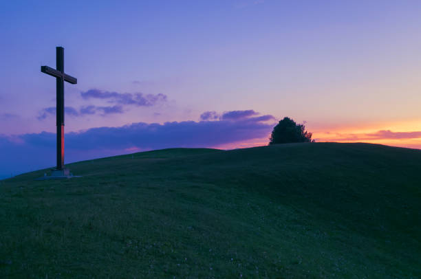 Christian cross on the hill and sunset sky in background