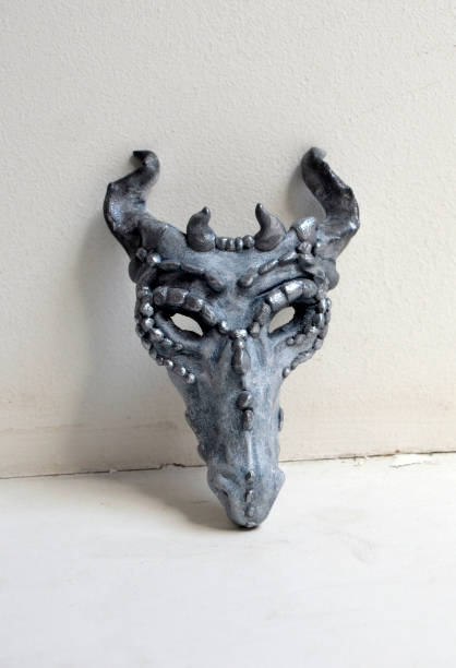 istock Dragon mask standing by a white wall 938565058