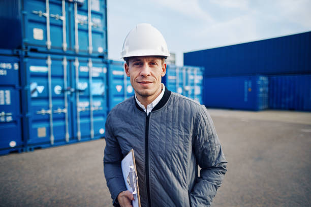 istock Smiling dock foreman standing in a commercial shipping yard 938570514