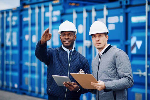 istock Smiling engineers tracking freight containers in a large shipping yard 938572628