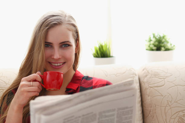 istock woman drinking coffe and reading sit on sofa 938579314