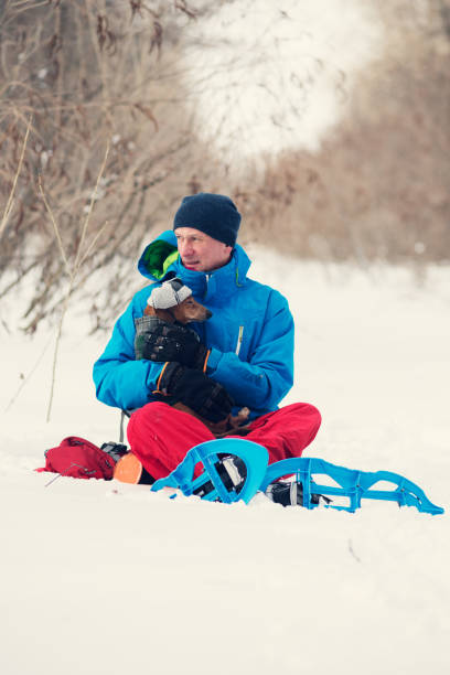 istock Traveler in snowshoes  hugging funny dog 938582002
