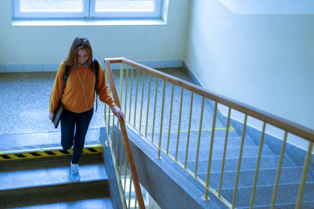 junge depressiv einsame weibliche college-student zu fuß die treppe hinunter in ihrer schule, blick nach unten. bildung, mobbing, depression-konzept. - university education walking teenage girls stock-fotos und bilder