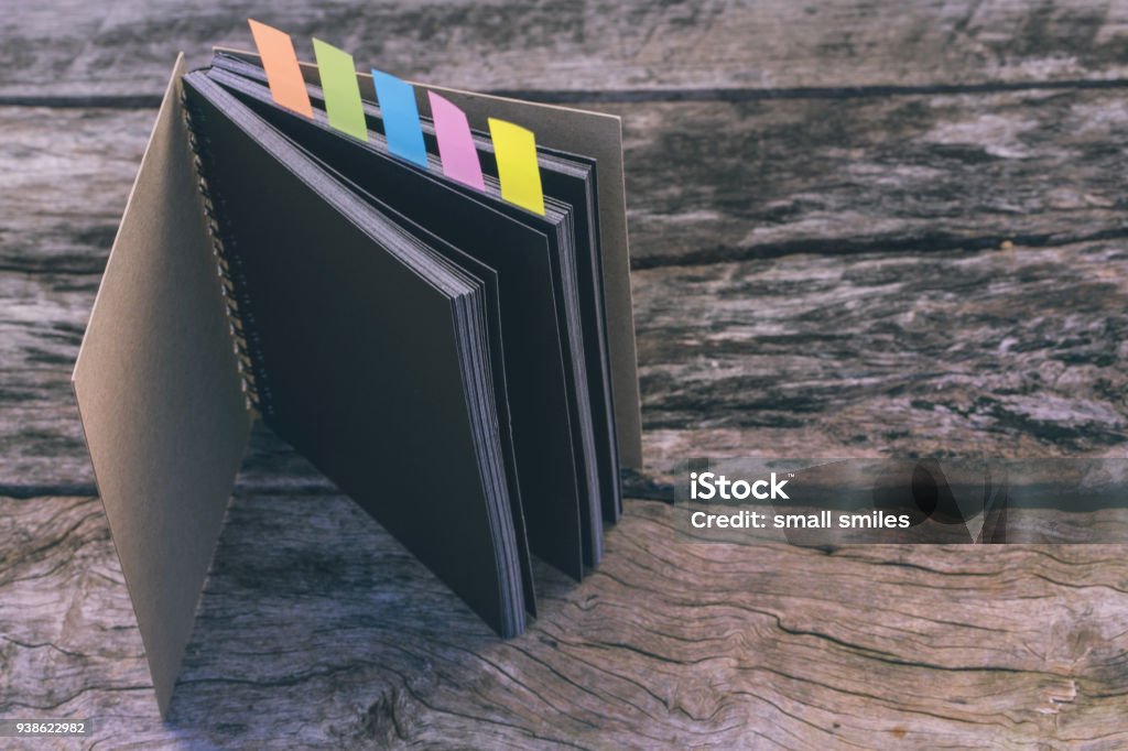 Abstract sketchbook with color note tab. Notebook with colors note tab on wooden table background, Vintage picture tone. Archives Stock Photo