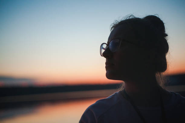 istock Silhouette girl in glasses sunset 938623080