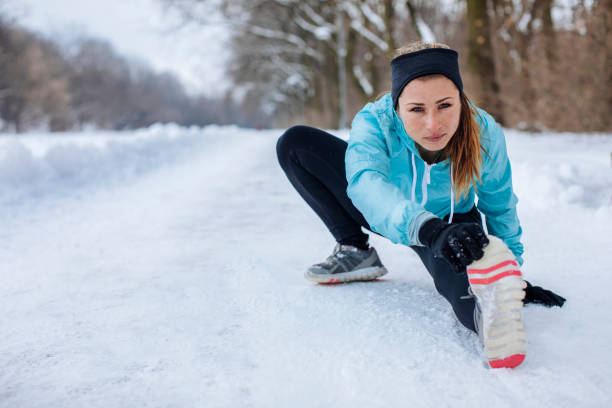 Pretty young woman outdoors in the winter stretching before sports training