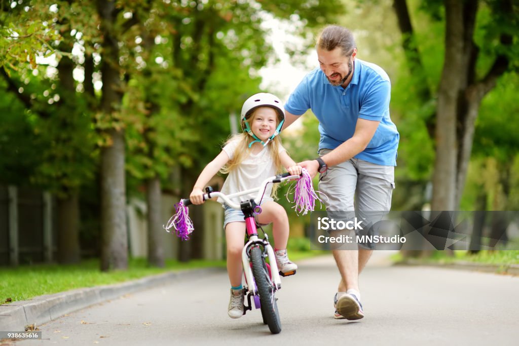 Glücklicher Vater Lehre sein Töchterchen, Fahrrad zu fahren. Kinder lernen, mit dem Fahrrad. - Lizenzfrei Radfahren Stock-Foto