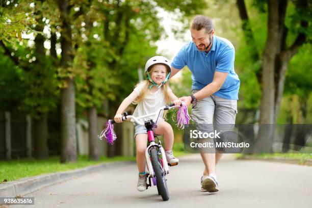 幸せな父が自転車に乗る彼は小さな娘を教えます子供は自転車に乗ることを学ぶします - サイクリングのストックフォトや画像を多数ご用意 - サイクリング, 父親, 子供