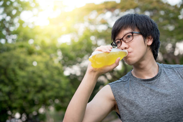 istock Young Asian man runner drinking energy drink after jogging in the park 938636464
