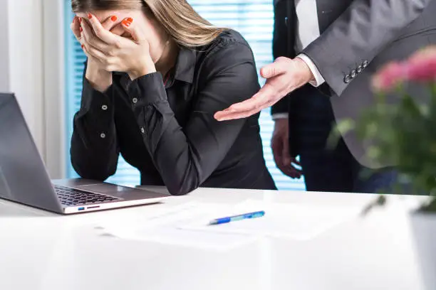 Photo of Upset woman crying in office. Getting fired from job. Business man or boss apologizing, comforting or supporting assistant. Businesswoman hurt her feelings or made mistake.