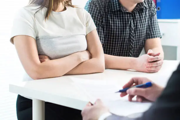 Photo of Unhappy couple in meeting with therapist, psychologist, divorce lawyer or legal consultant. Upset woman and man having fight in therapy session or marriage counselling.