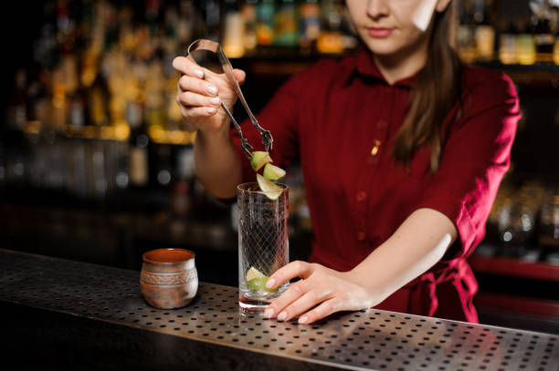 istock Female bartender putting a three pieces of lime into a glass 938641206