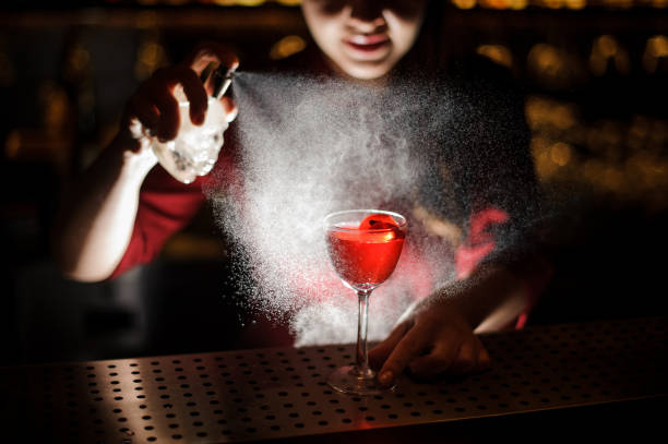 istock Female bartender spraying on the red cocktail for serving it 938644750