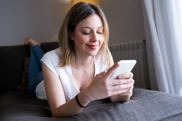 istock Beautiful happy young woman using her mobile phone at home. 938648912