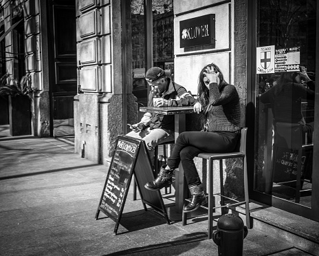 Milan, Italy - March 23, 2016:  Younf female sitting at outdoor street cafe and drinking the coffee in Milan, Italy