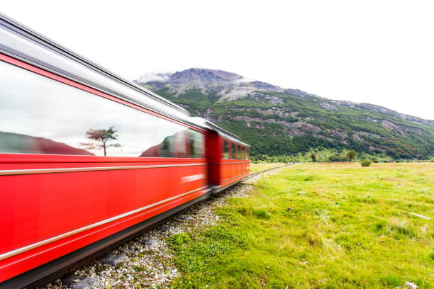 istock Long exposure of red train riding along green grassy field 938649326