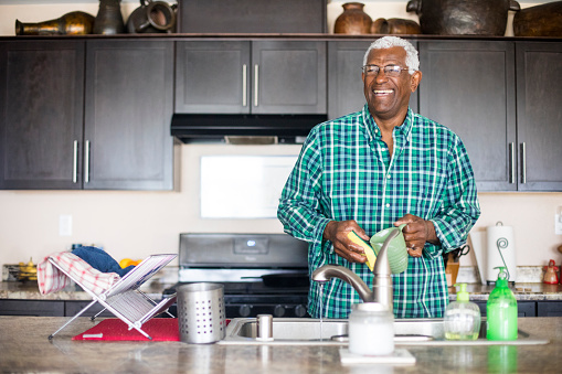 A senior black man cleaning dishes
