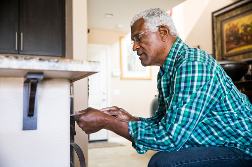 A senior Black man doing a simple home repair