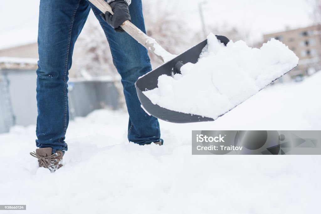 lose up view of snow shovel wih snow in man's hands. Man clean backyard of his hause after blizzard. close up view of snow shovel with snow in man's hands. Man clean backyard of his house after blizzard. Spring snow cleaning. Snow Stock Photo