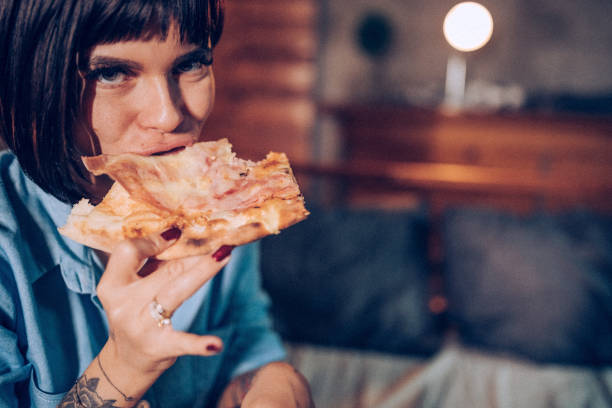 istock Lonely tattooed woman eating pizza in bed 938661920