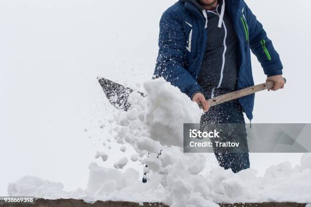 Young Man Clean A Roof From Snow By Shovel Spring Snow Removing After Blizzard Stock Photo - Download Image Now