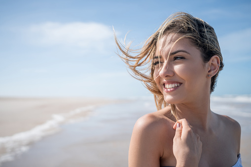 Portrait of a beautiful young woman at the beach looking very happy and smiling - lifestyle concepts
