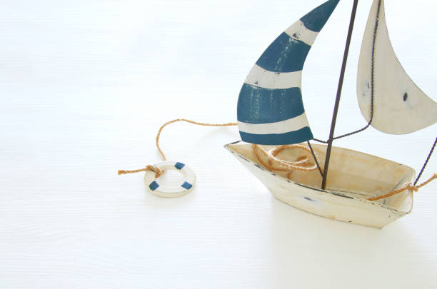 istock nautical concept with white decorative sail boat over white wooden table. 938670686