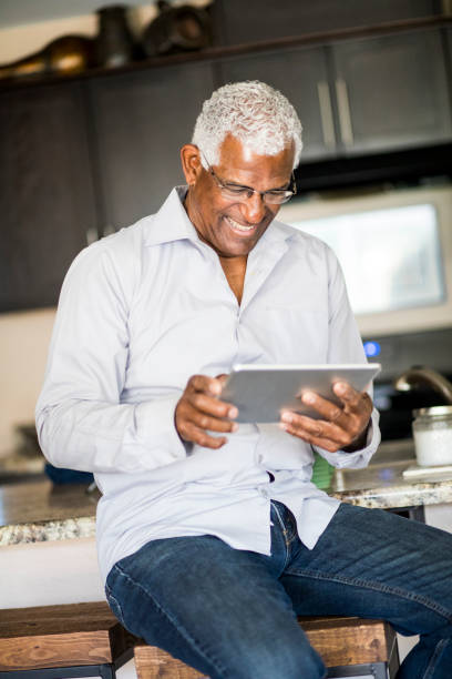 istock Senior Black Man Browsing on Tablet at home 938670742