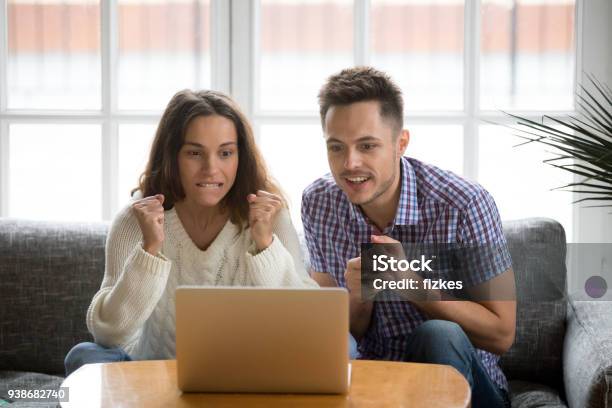 Couple Looking At Laptop Screen Supporting Team Watching Match Online Stock Photo - Download Image Now