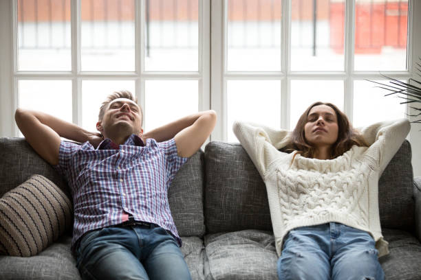 istock Relaxed young man and woman enjoying relaxation on comfortable couch 938682756