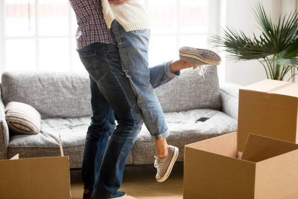 istock Man lifting woman standing among cardboard boxes, close up view 938682826