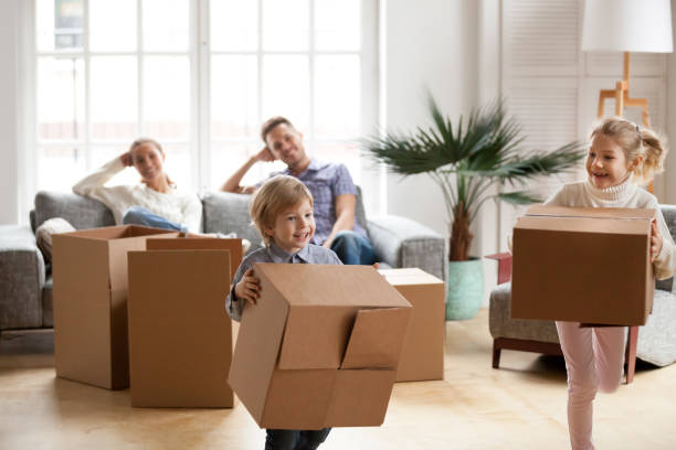 istock Cute small kids carrying boxes playing together on moving day 938682828