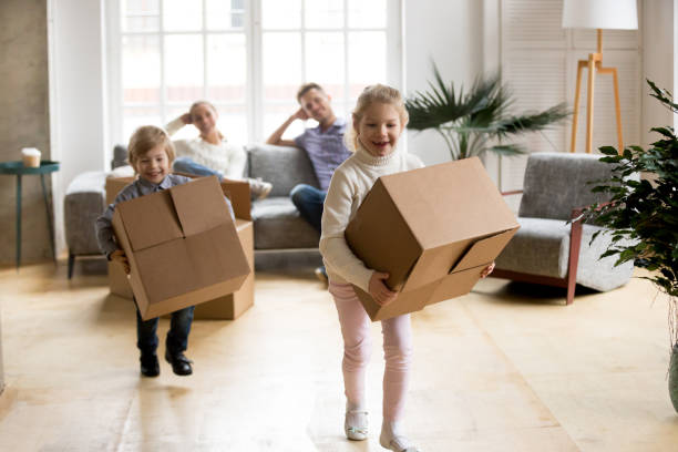 istock Excited kids playing holding boxes after moving in new home 938682842