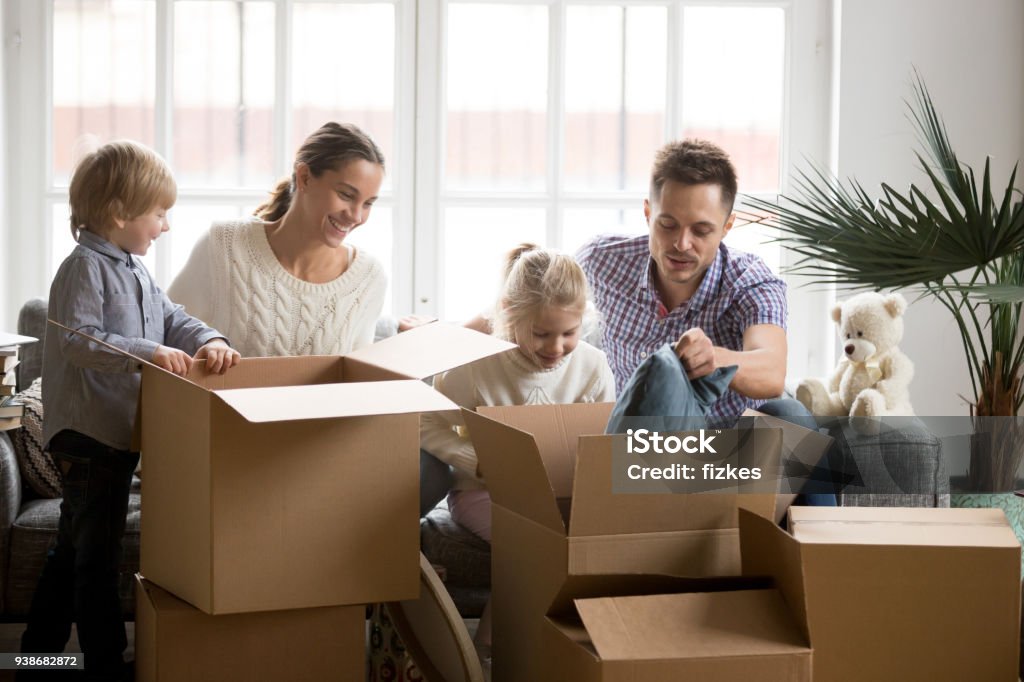 Junge glückliche Familie mit Kindern Verpackungskästen am Umzugstag - Lizenzfrei Familie Stock-Foto