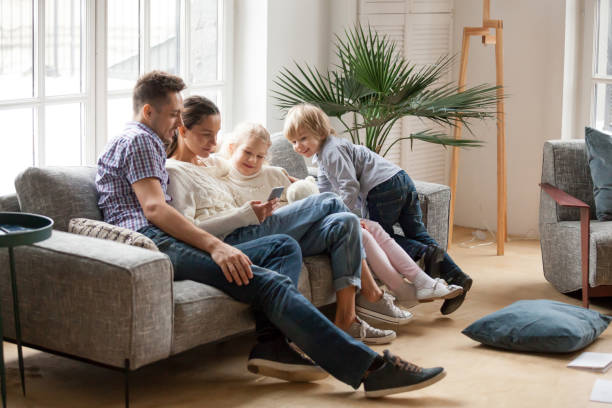 istock Happy family with children using mobile apps together on sofa 938682880