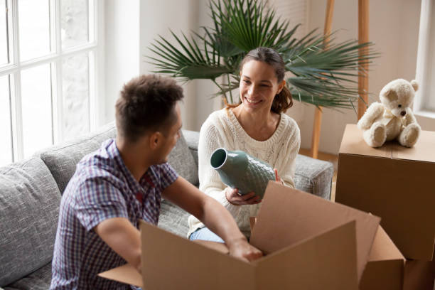 istock Woman holding vase helping man packing boxes on moving day 938682912