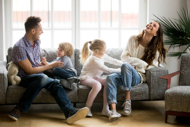 istock Happy parents and kids having fun tickling sitting on sofa 938682934