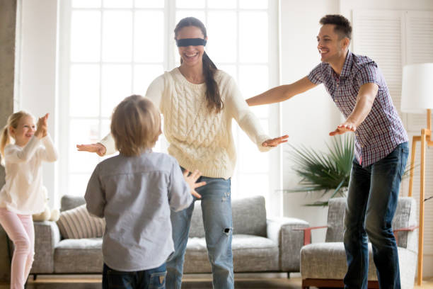 istock Family playing hide and seek game together with blindfolded mother 938682954