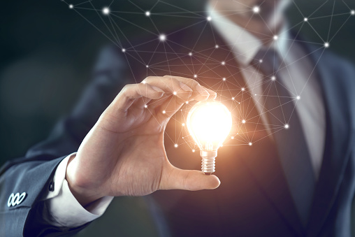 Hand of businessman holding illuminated light bulb, idea, innovation and inspiration concept.