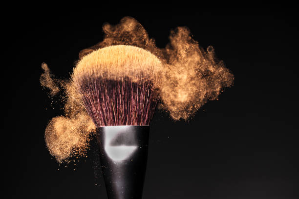 face powder in motion on a make-up brush on a black studio background - face powder imagens e fotografias de stock