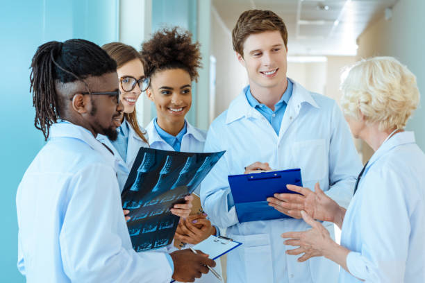 medical interns listening to teacher A multiracial group of young medical interns listening to a elder doctor in a hospital corridor medical student stock pictures, royalty-free photos & images