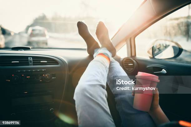 Woman Is Holding Cup Of Coffee Inside Of Car Travel Lifestyle Legs On Dashboard Stock Photo - Download Image Now