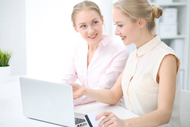 istock Two business ladies or colleagues discussing something in office background 938701606