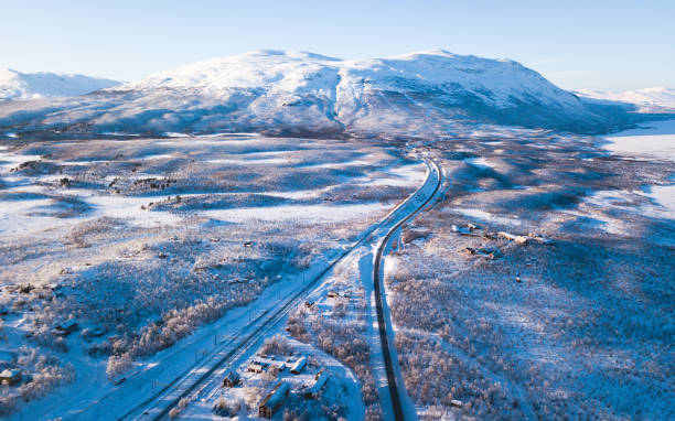 Aerial sunny winter view of Abisko National Park, Kiruna Municipality, Lapland, Norrbotten County, Sweden, shot from drone, with road and mountains stock photo
